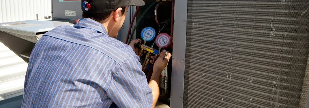 HVAC technician servicing a condenser unit in Kronenwetter