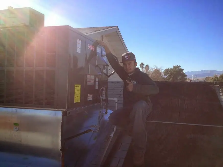 HVAC technician performing AC Tune-Up on a rooftop unit in Kronenwetter